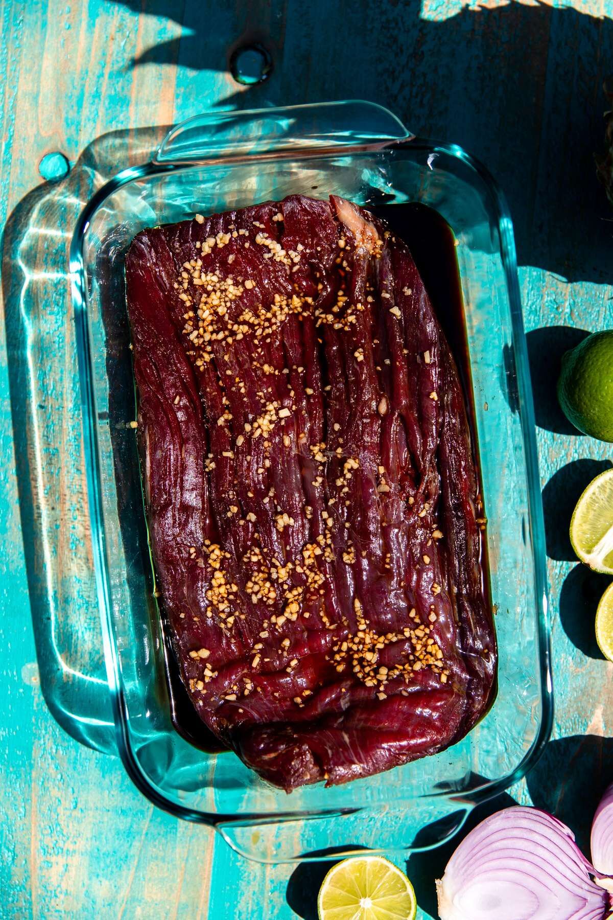 A flank steak marinating in a dish of Asian-inspired marinade. 