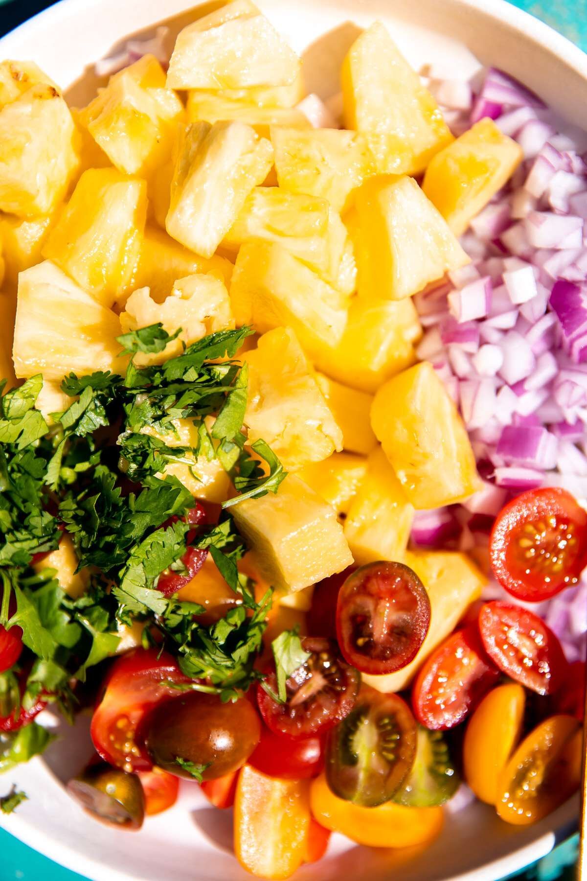 A close-up photo of a bowl of pineapple salsa before all of the ingredients have been mixed together. 
