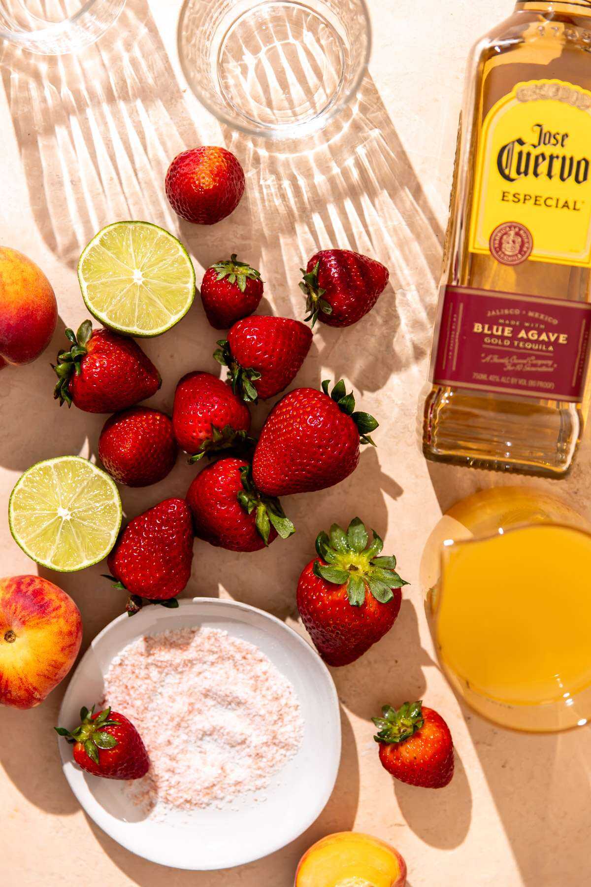 All of the ingredients needed for Strawberry Smash Peach Margaritas waiting to be used. 
