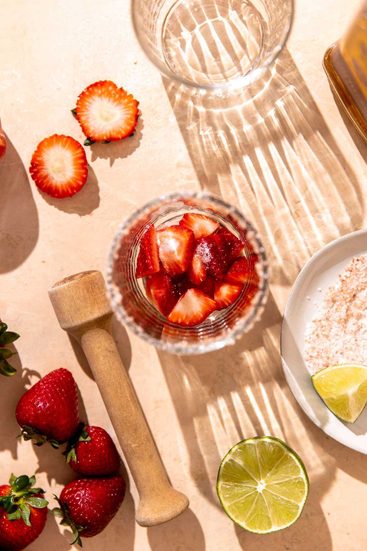 Strawberries in the bottom of a margarita glass waiting to be muddled.