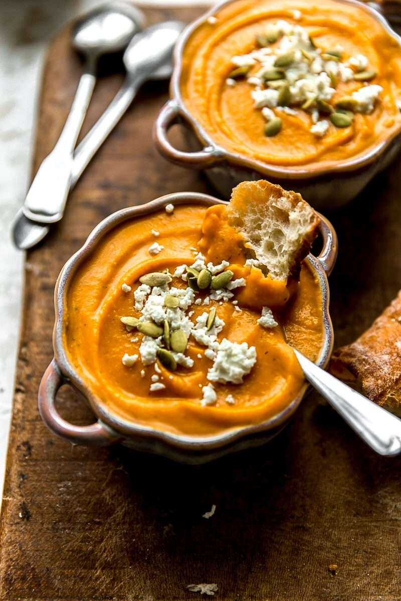 A close-up photo of roasted butternut squash soup in festive bowls with toppings.
