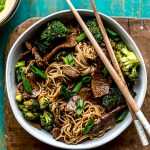 Teriyaki Beef & Broccoli Noodle Bowls served with green onions and chop sticks.