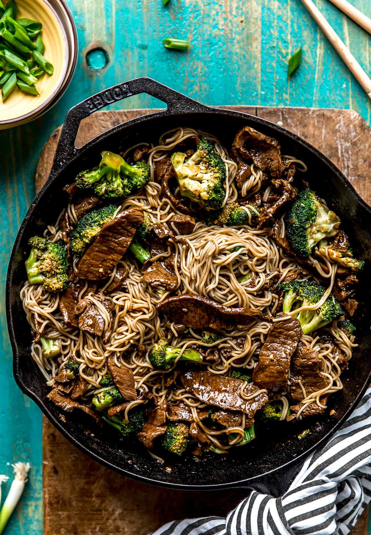 Ramen noodles being mixed into the teriyaki beef and broccoli in a skillet. 