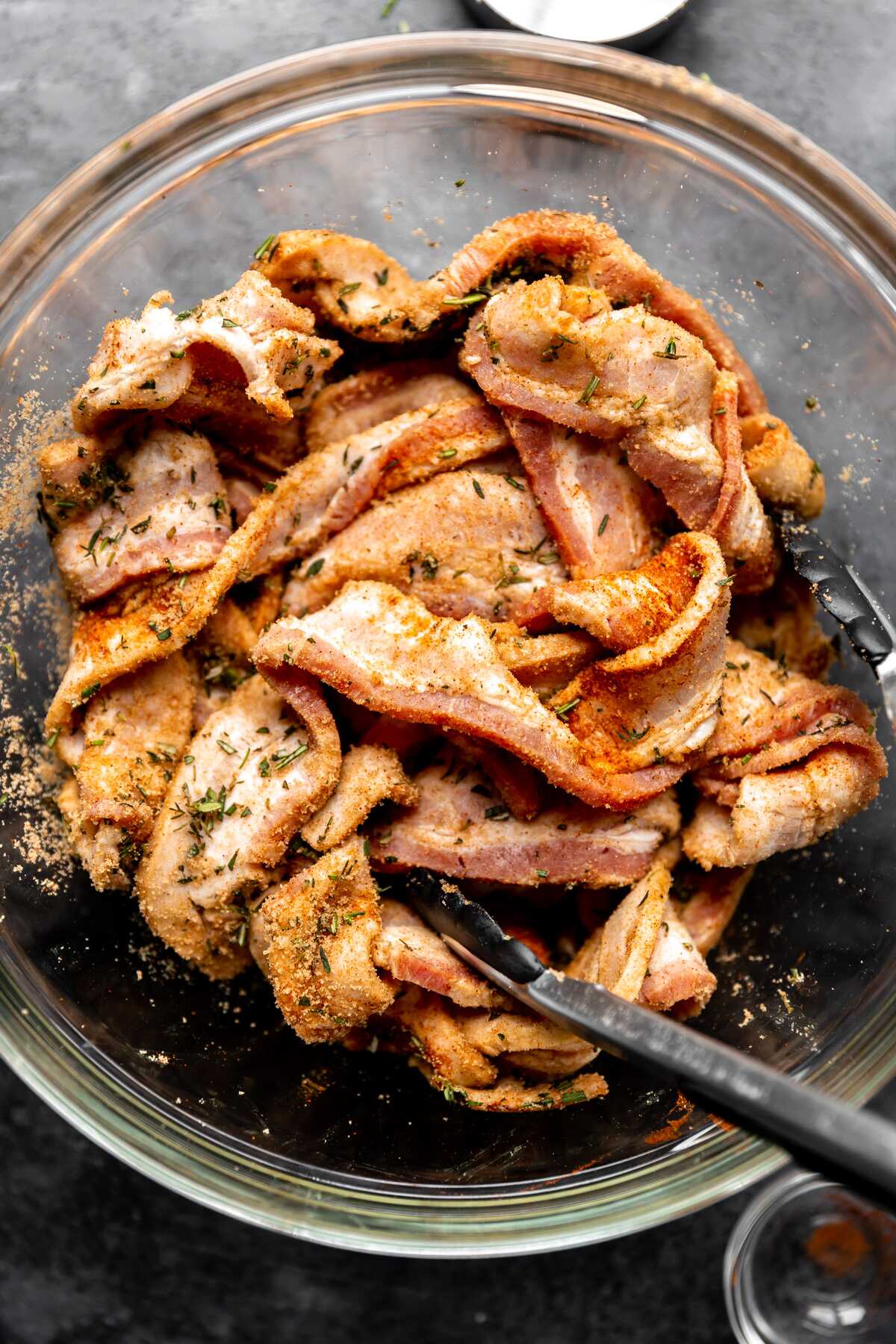 Seasoned herb candied bacon ready for the baking sheet.