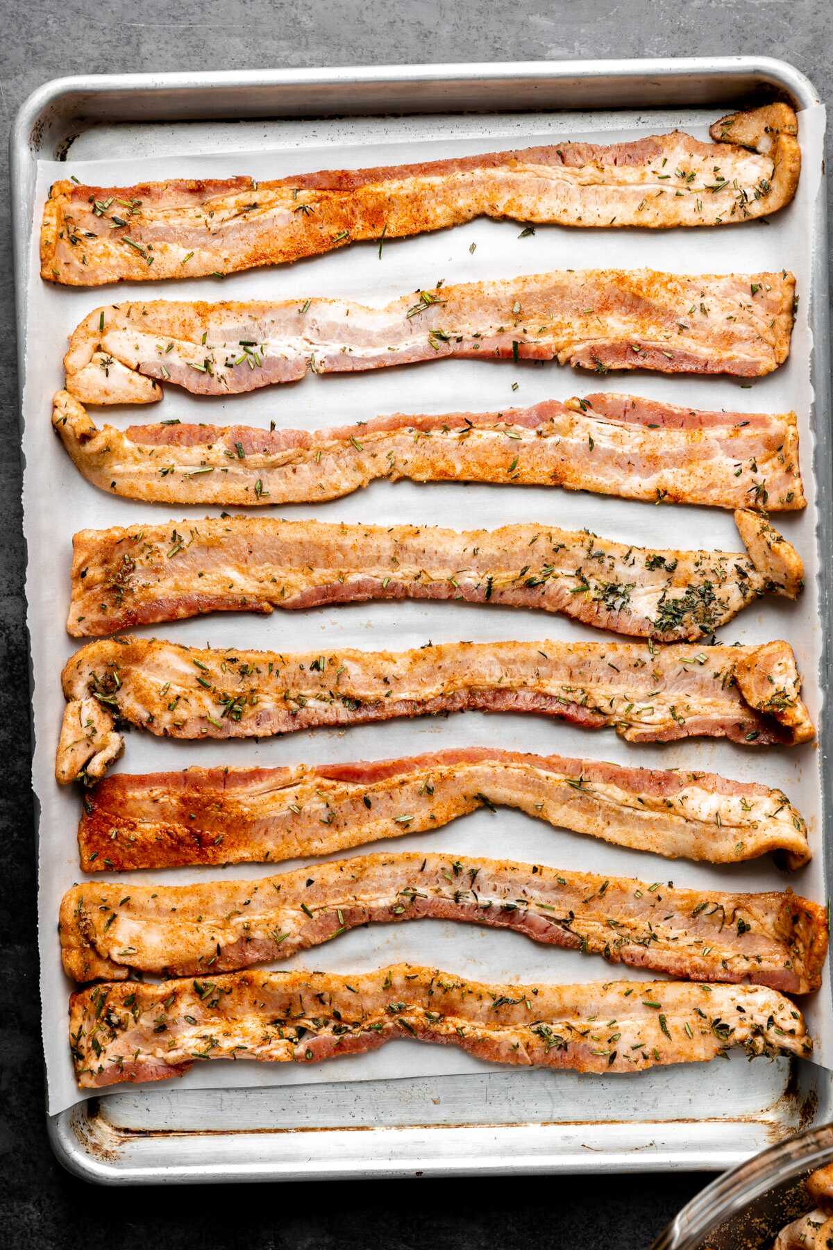Herb candied bacon on a baking sheet prior to baking.