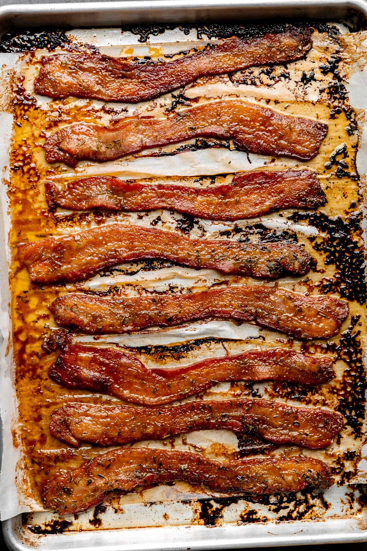 Baked herb candied bacon on a sheet pan.