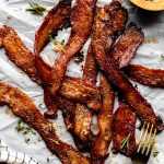 Herb Candied Bacon arranged on parchment paper.