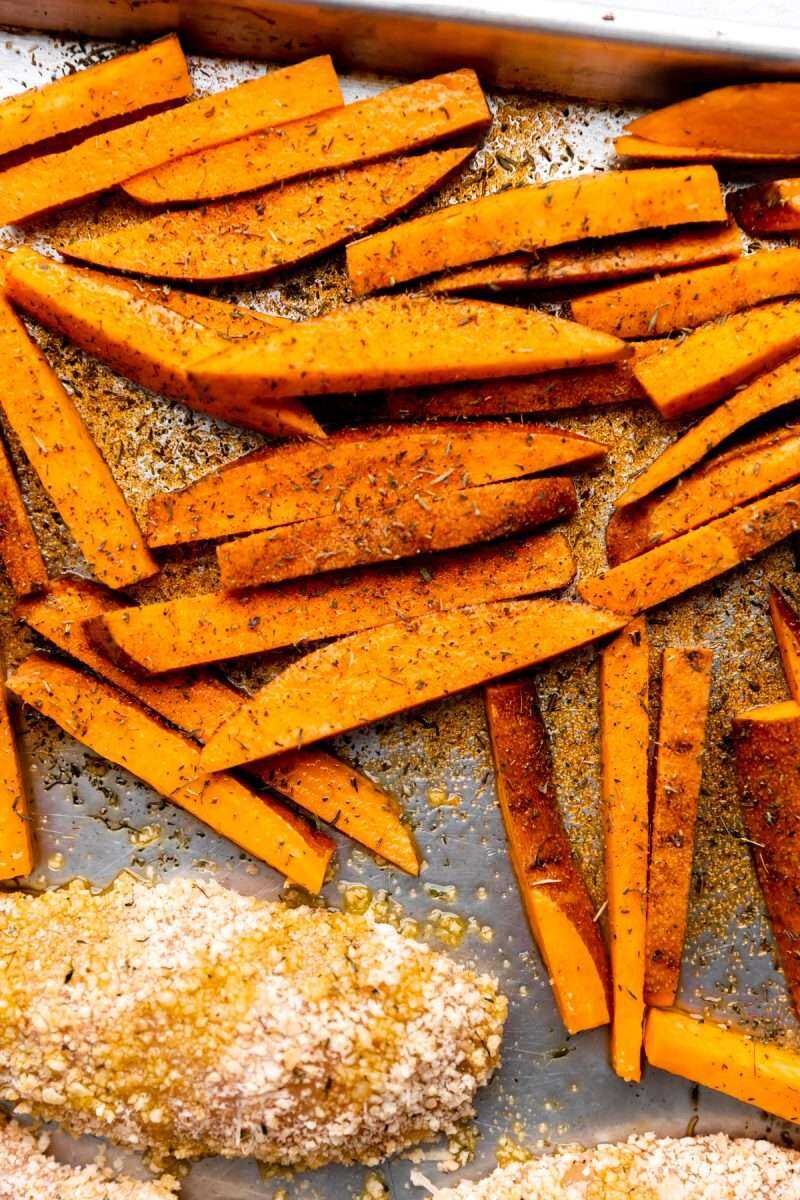 A close-up photo of the seasoned sweet potato fries on the baking sheet ready for the oven.