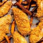 Crispy parmesan chicken fingers on a sheet pan with sweet potato fries