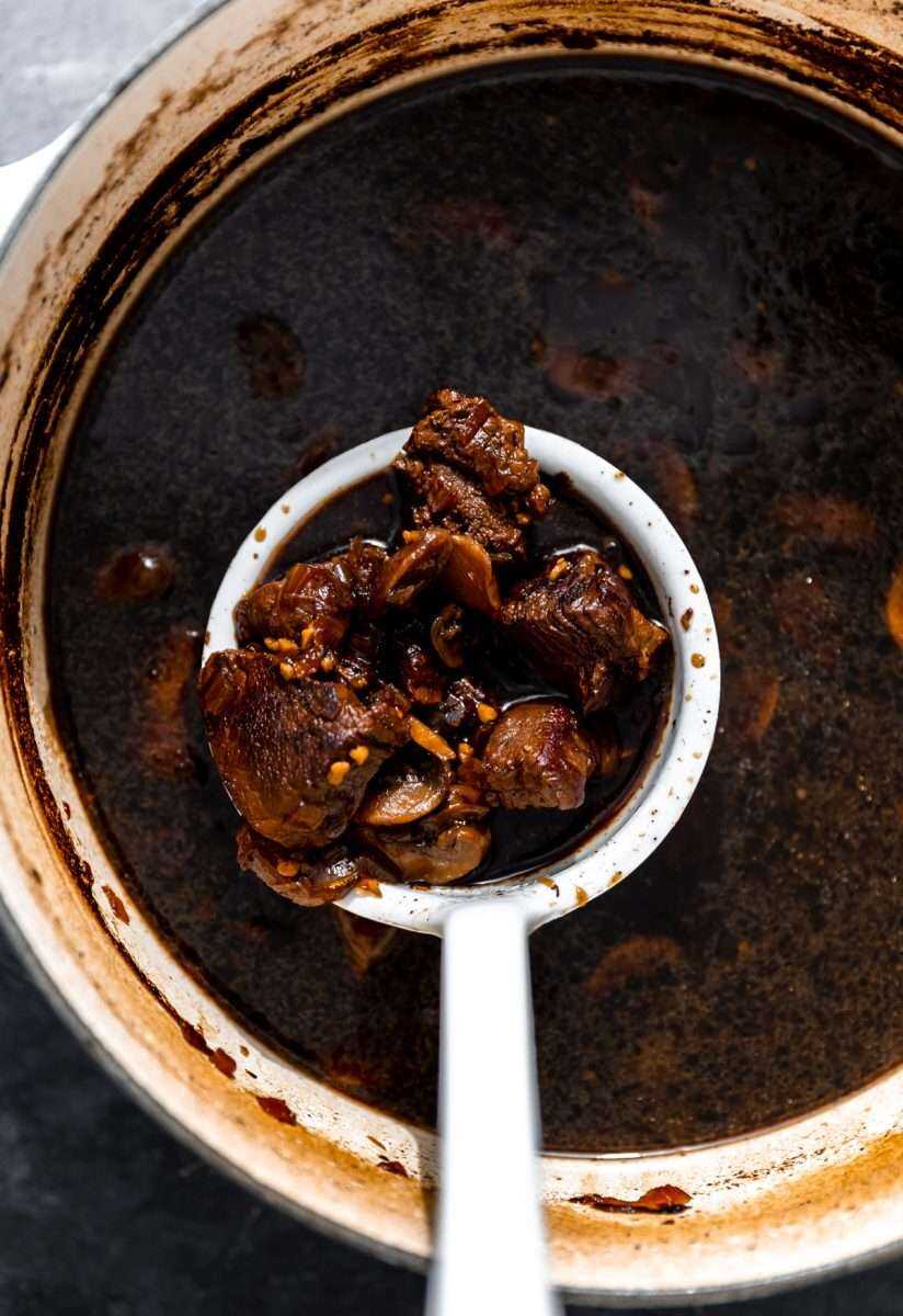 A ladle full of beer braised beef ramen.