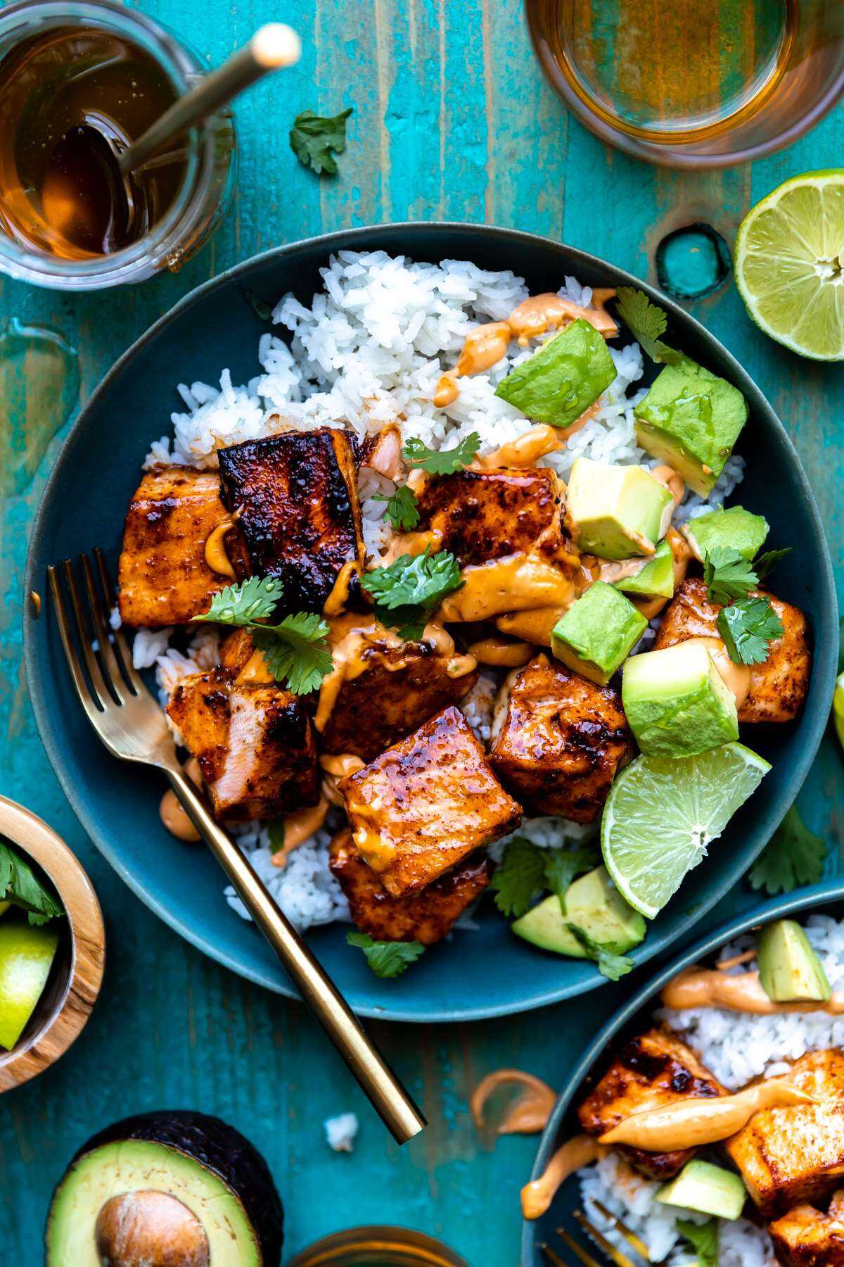 Honey Chipotle Salmon in a blue bowl on top of white rice topped with diced avocado and cilantro.