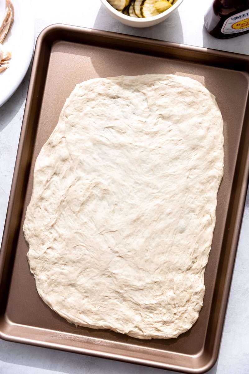 Pizza dough rolled out onto a sheet pan.