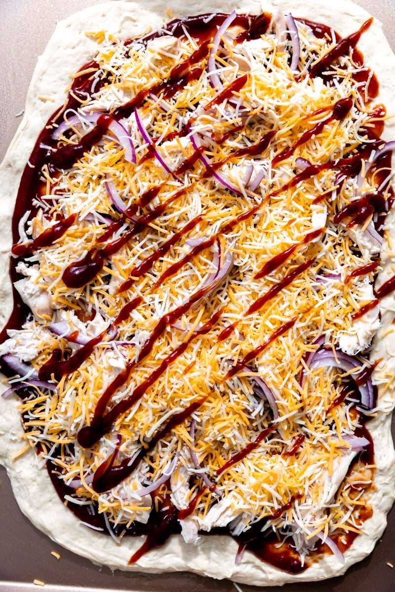 Extra bbq sauce drizzled over the top of a bbq chicken pizza before baking.
