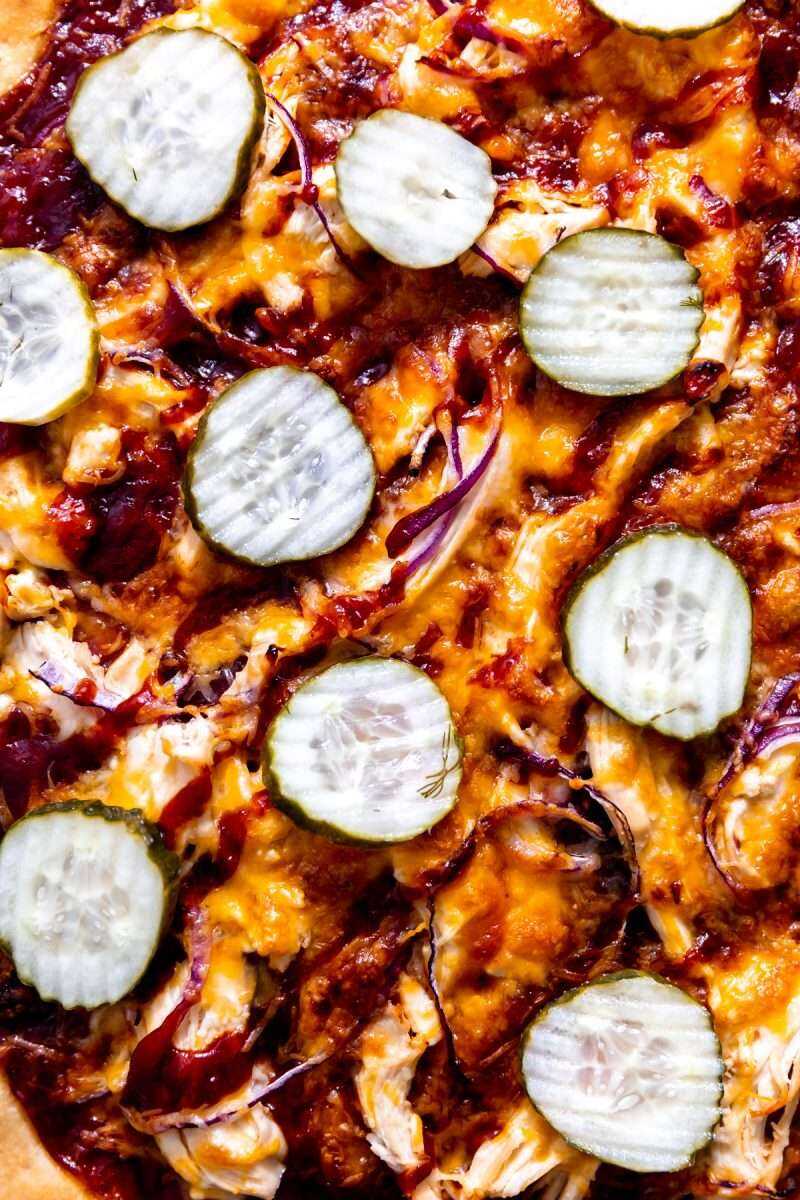 Pickles topping off a baked bbq chicken pizza.