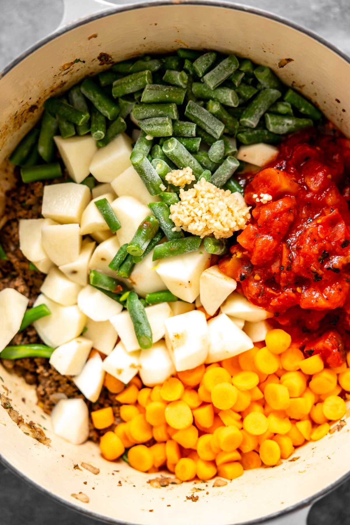 Diced potatoes, frozen green beans, diced tomatoes and carrot rounds added to the soup pot. 