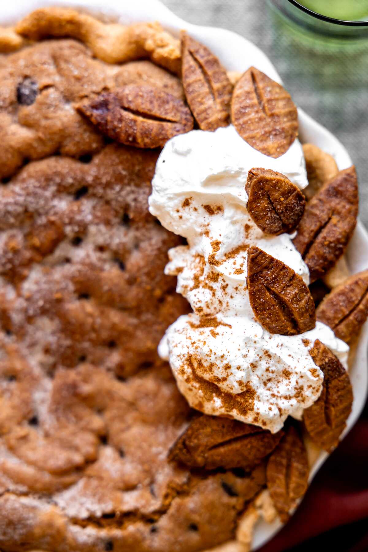 Whipped cream and pie crust leaves decorating a cinnamon chocolate chip cookie pie. 