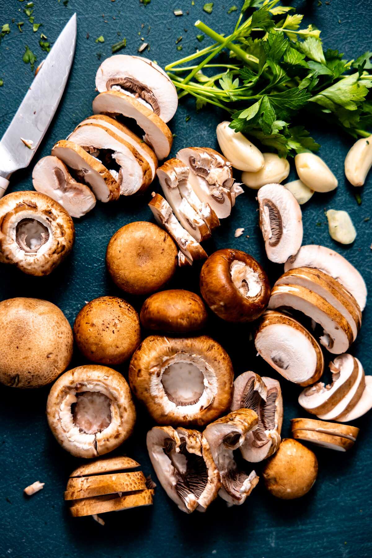 Sliced mushrooms and garlic on a cutting board.