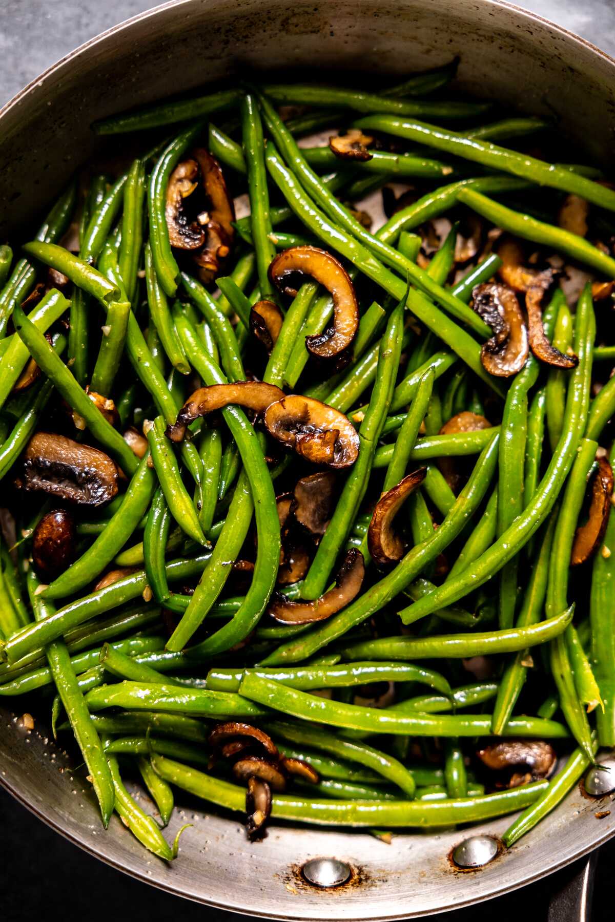 Sautéd green beans and mushrooms in a skillet. 