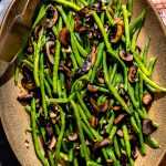 Garlic Mushroom Green Beans on a serving platter with tongs.