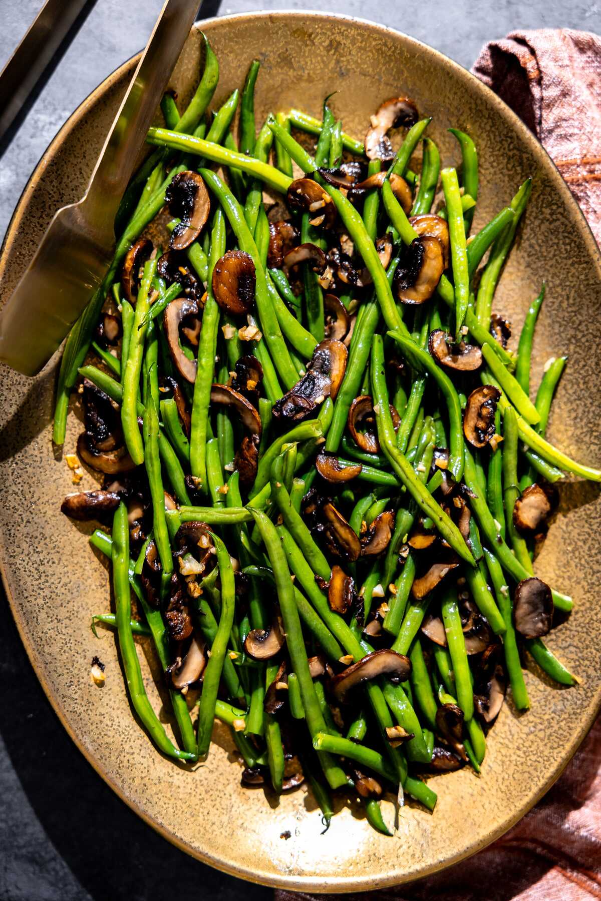 Garlic Mushroom Green Beans on a serving platter with tongs.