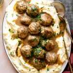 Herbed Turkey Meatballs with Gravy on a serving platter with mashed potatoes.