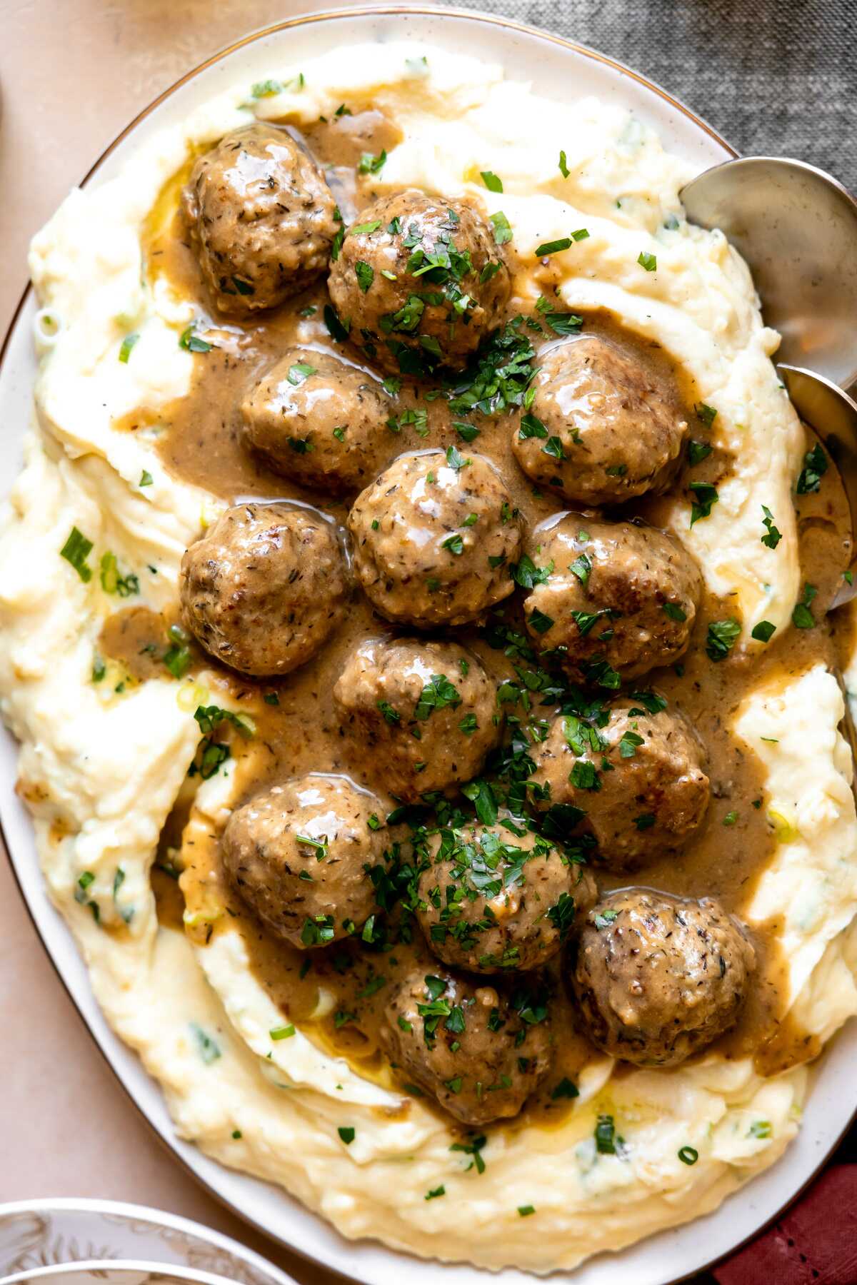 Herbed turkey meatballs in gravy on a platter of mashed potatoes. 
