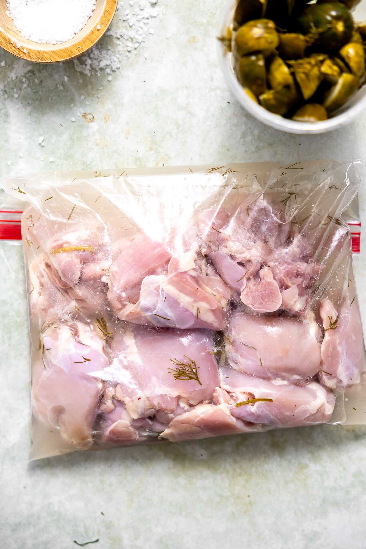 Chicken thighs marinating in pickle juice in a bag.