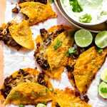 Cheesy Beef Sheet Pan Tacos ready to serve with limes and dipping sauces.