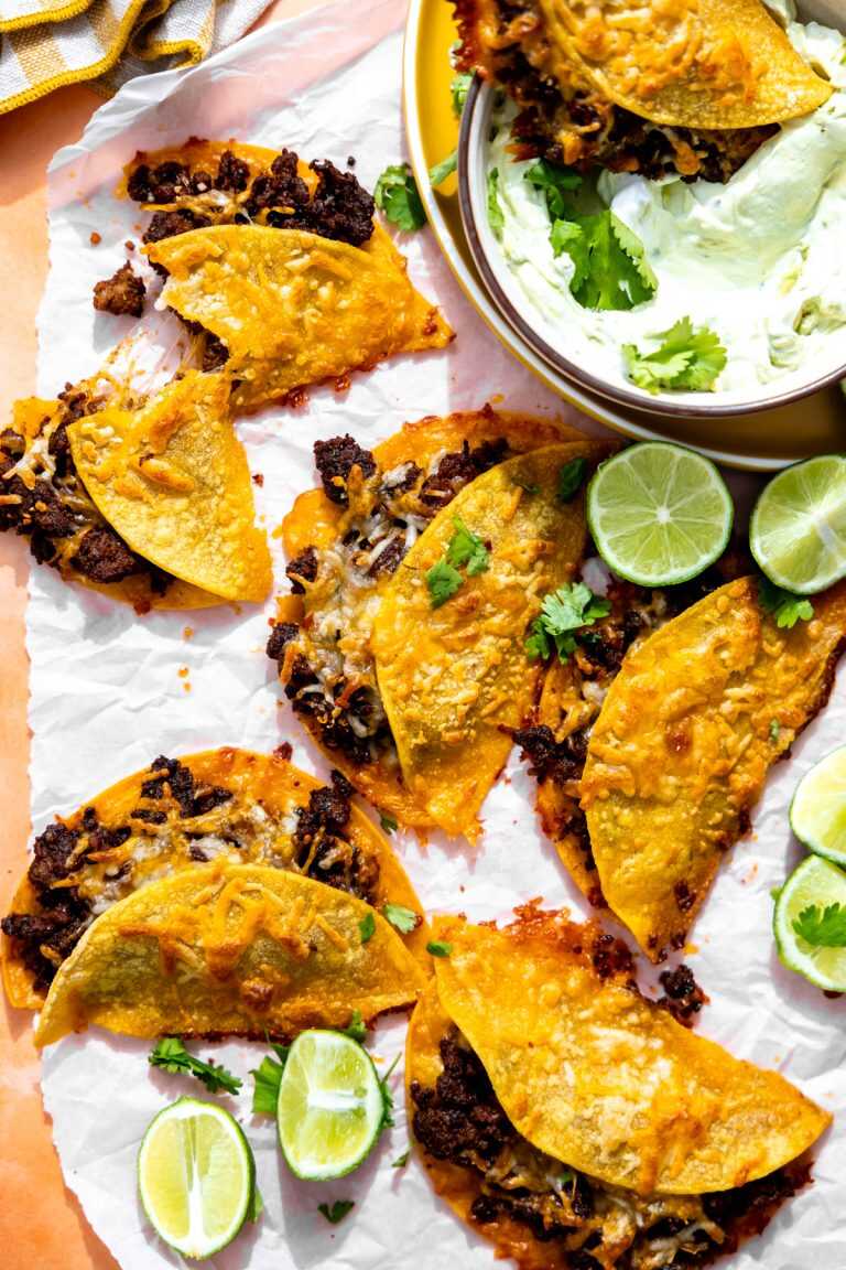 Cheesy Beef Sheet Pan Tacos ready to serve with limes and dipping sauces.