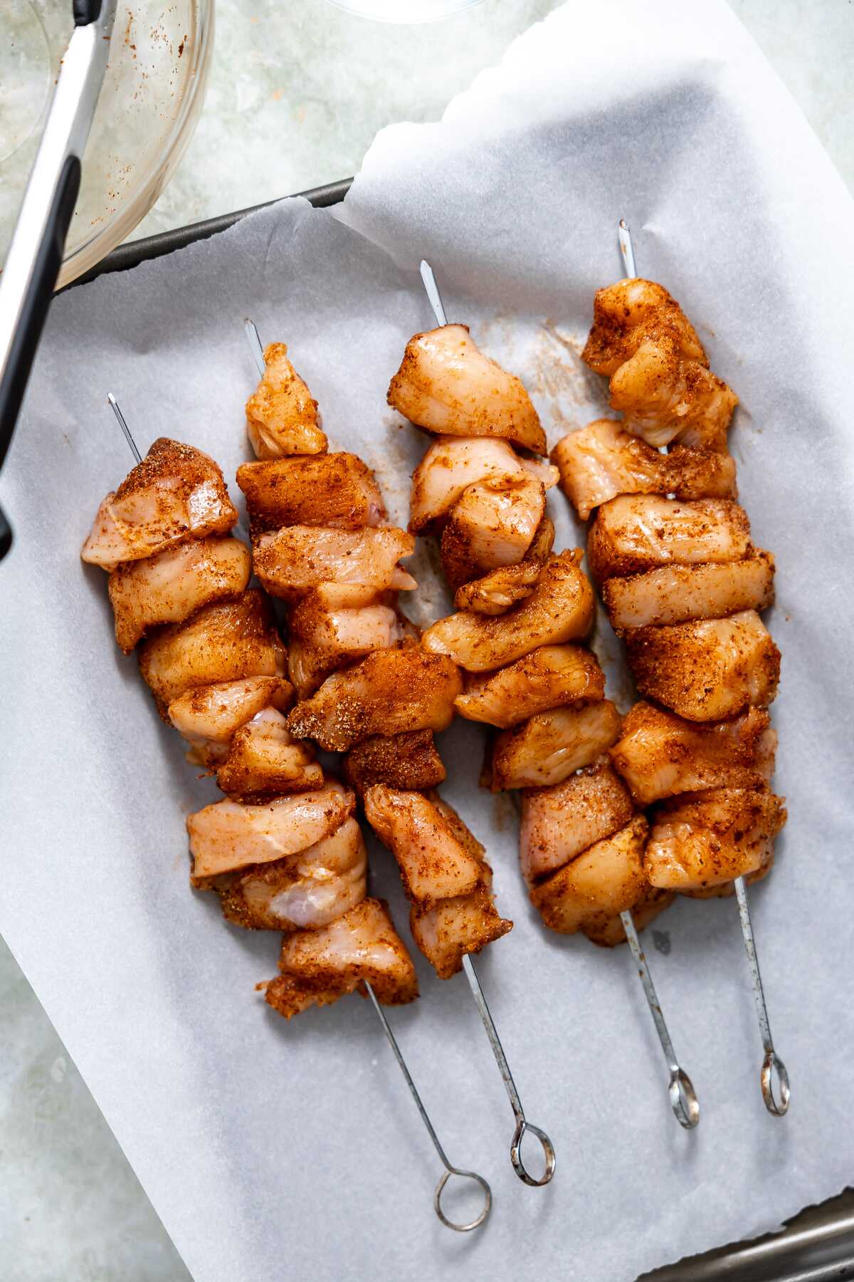 Seasoned and cubed chicken on skewers before grilling. 