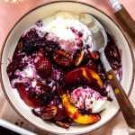 Fruit dump spooned over ice cream in a bowl.
