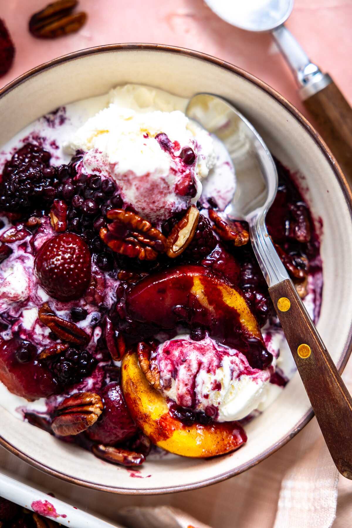Fruit dump spooned over ice cream in a bowl.