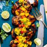 Grilled chicken with mango salsa on a serving board.