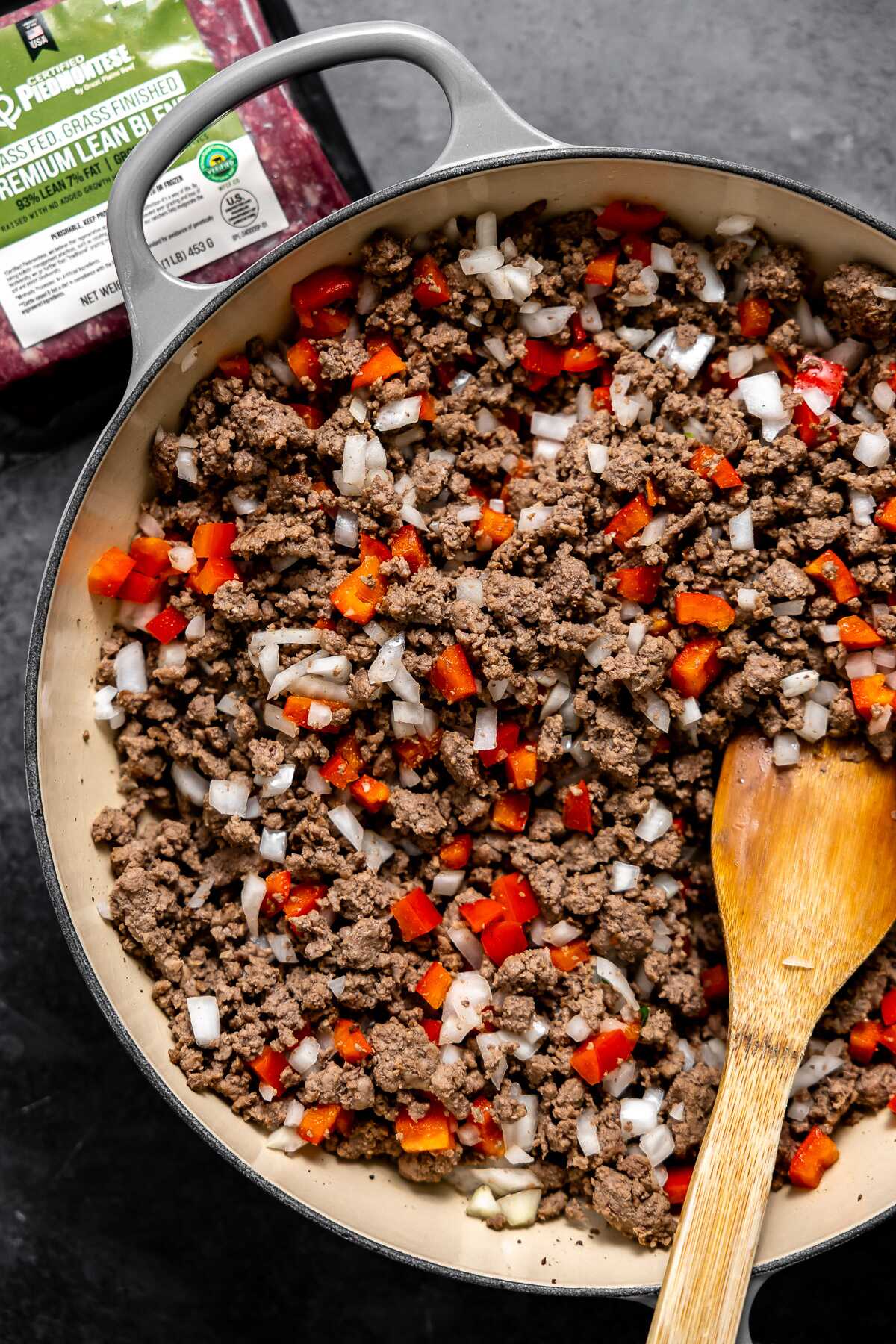 Ground beef sautéd in a skillet with onion and red bell pepper.
