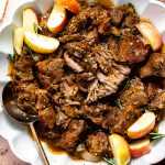 Apple cider pulled pork in a bowl topped with sliced apples