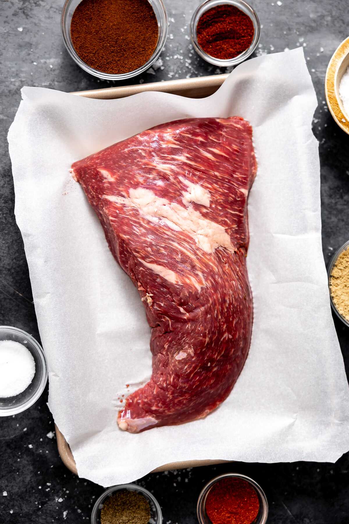 A tri-tip with the coffee dry rub ingredients around it. 