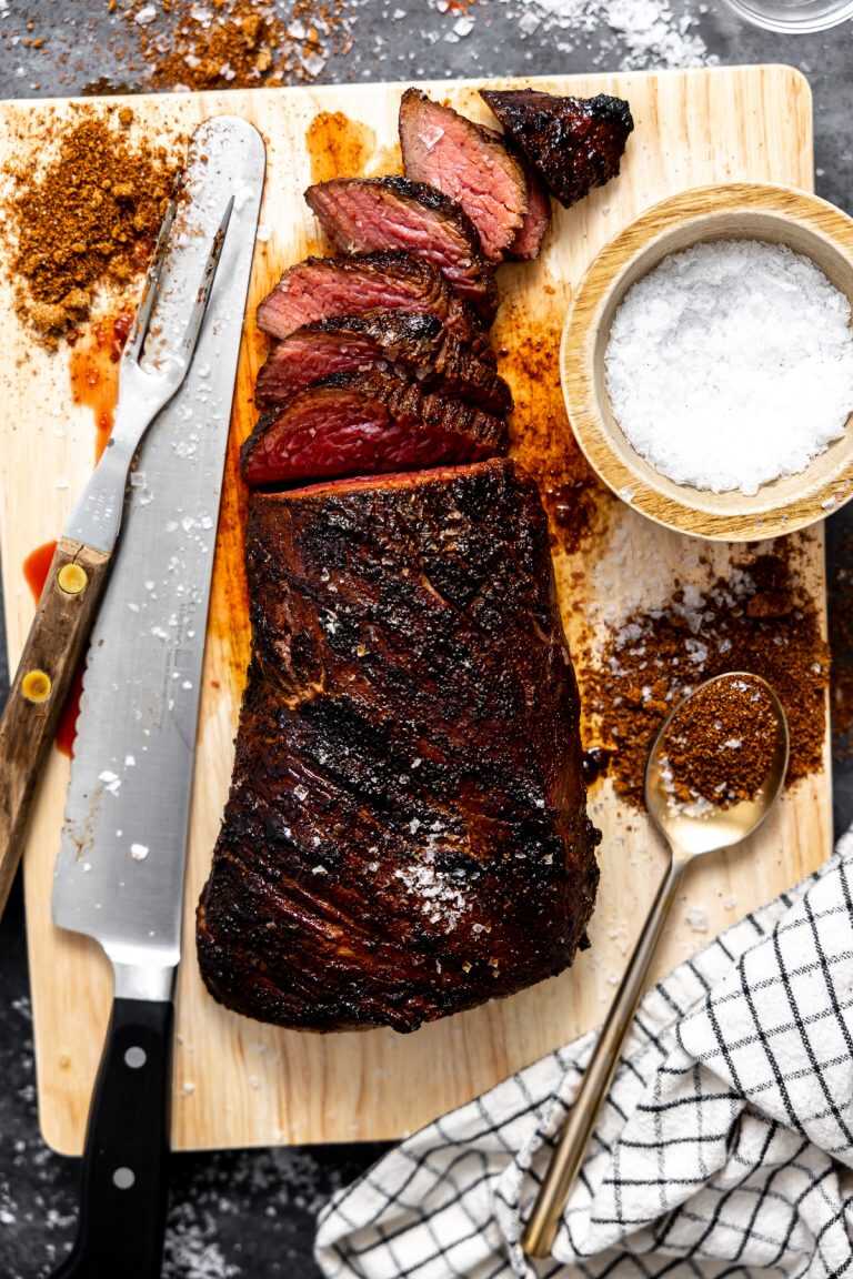 A coffee rubbed tri-tip being carved on a wooden cutting board.