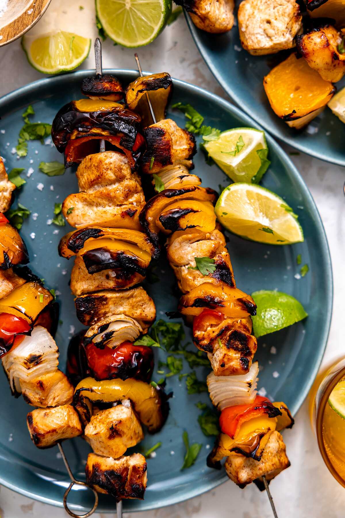 Grilled chicken fajita kabobs on a blue plate. 