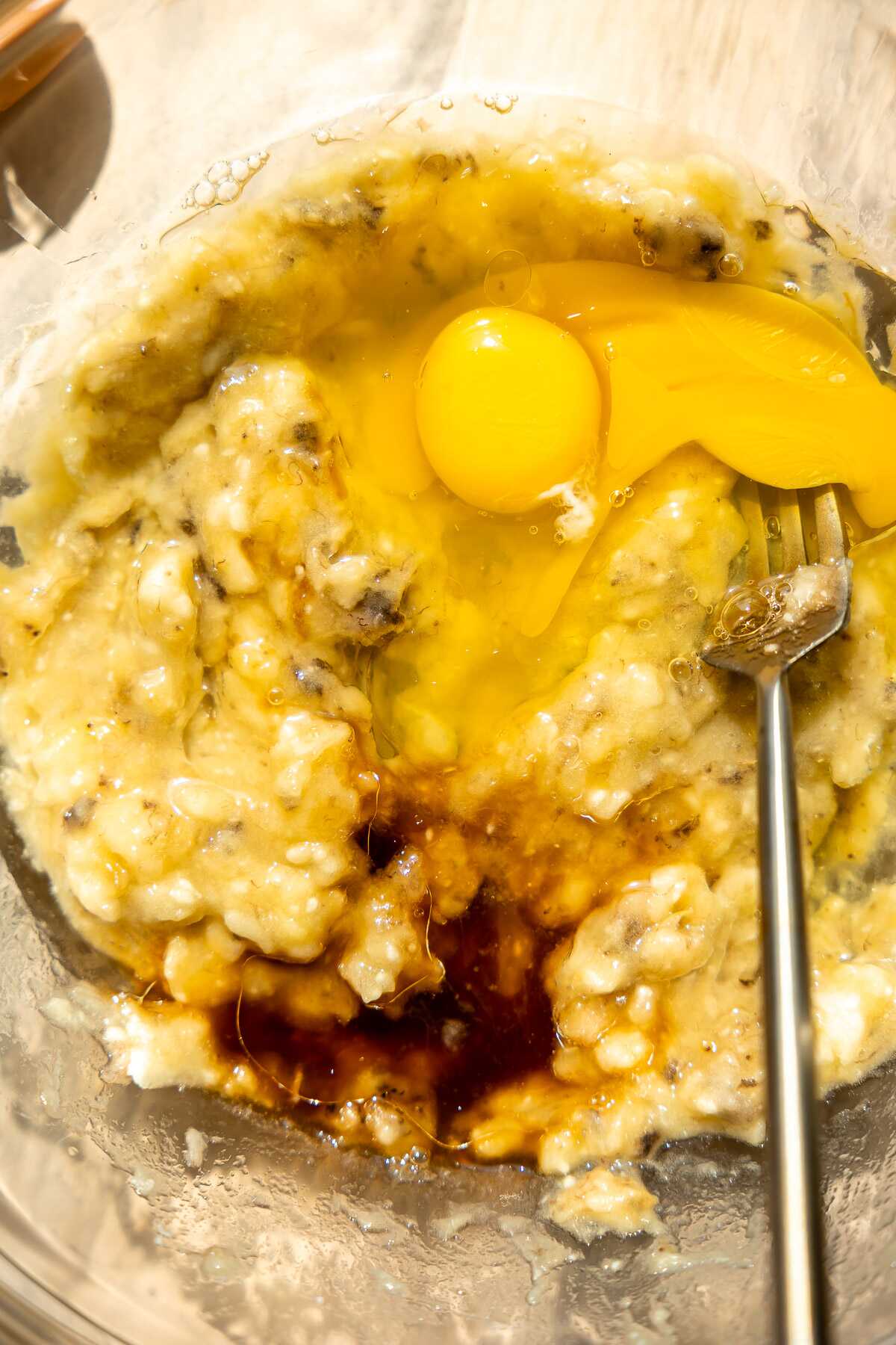 Eggs and vanilla being mixed into the mashed bananas.
