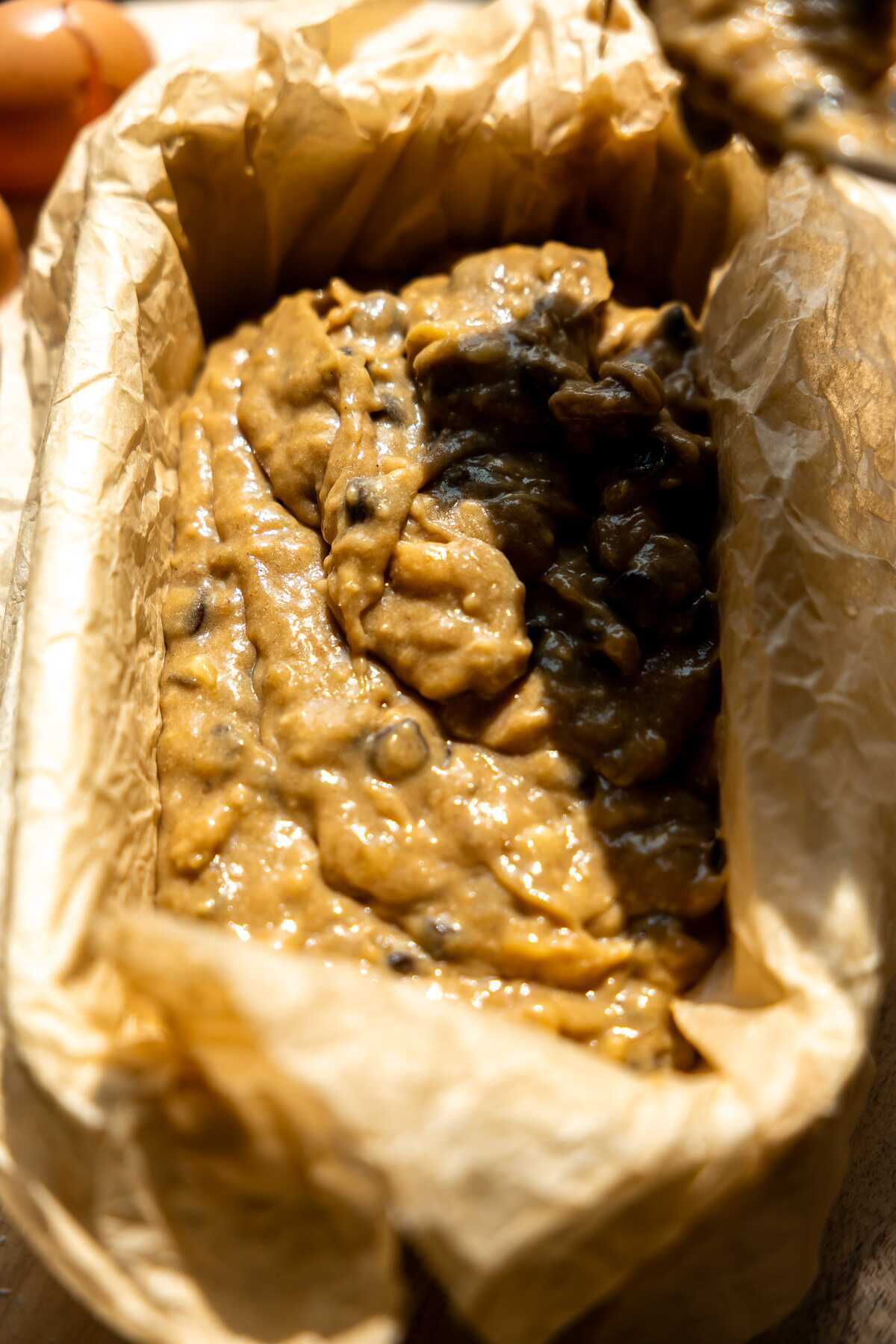 Banana bread batter being poured into a loaf pan.