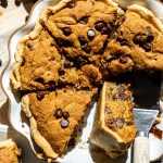 chocolate chip cookie pie cut up into to slices in dish.