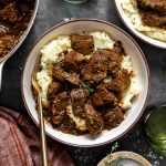 French onion braised beef tips served over mashed potatoes with a gold spoon