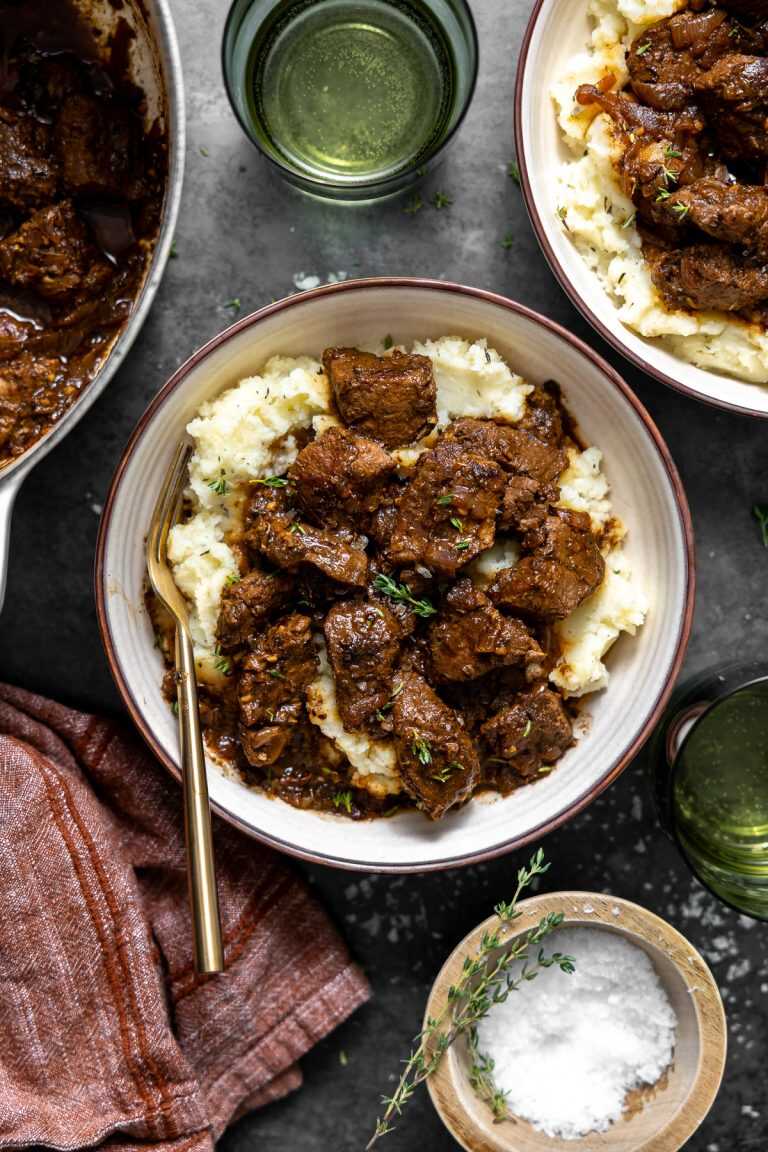French onion braised beef tips served over mashed potatoes with a gold spoon