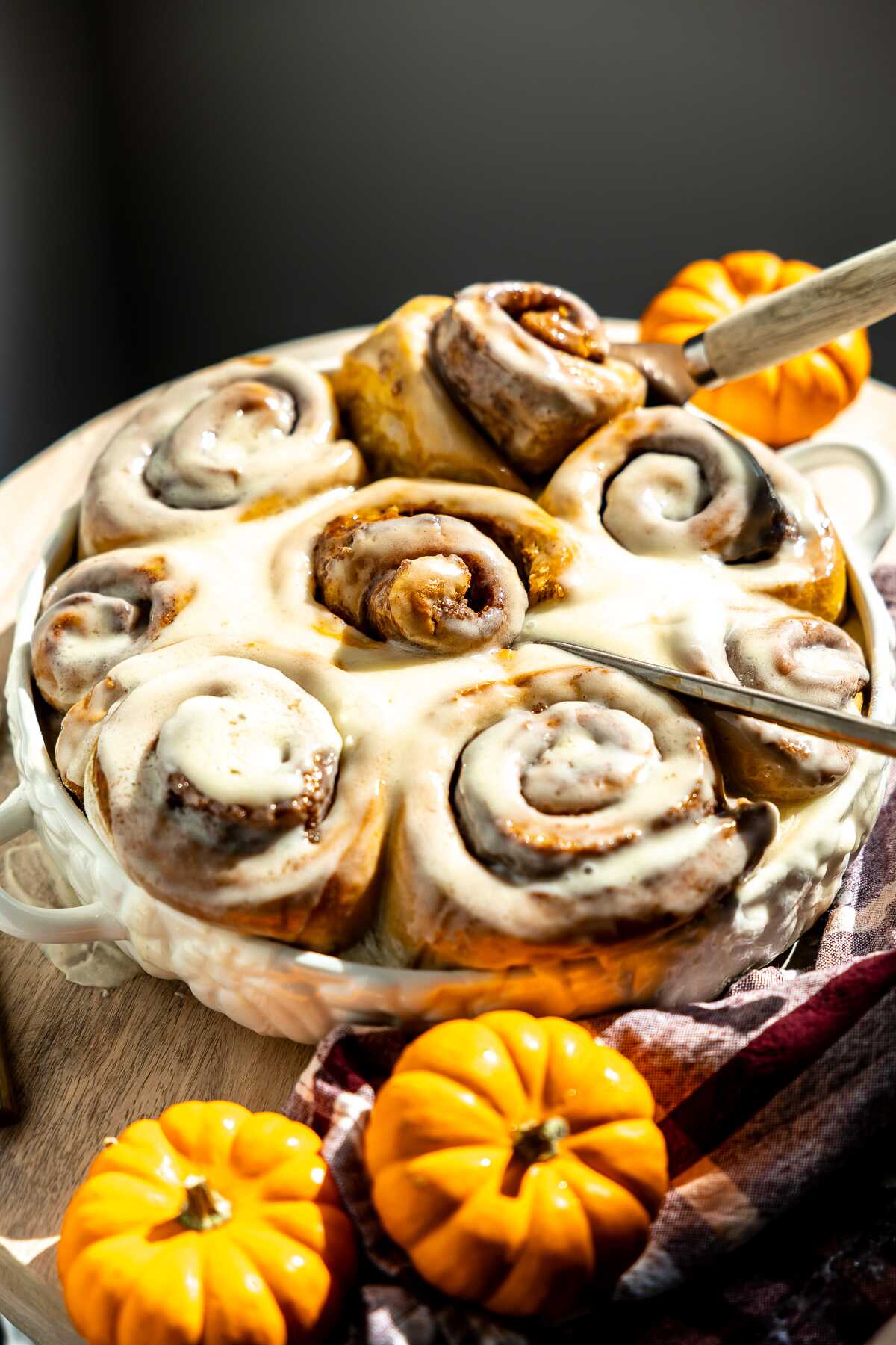 frosted pumpkin cinnamon rolls in a dish. 