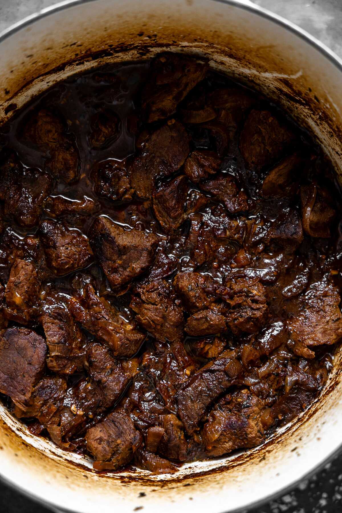 braised beef tenderloin cooking in sauce in dutch oven. 