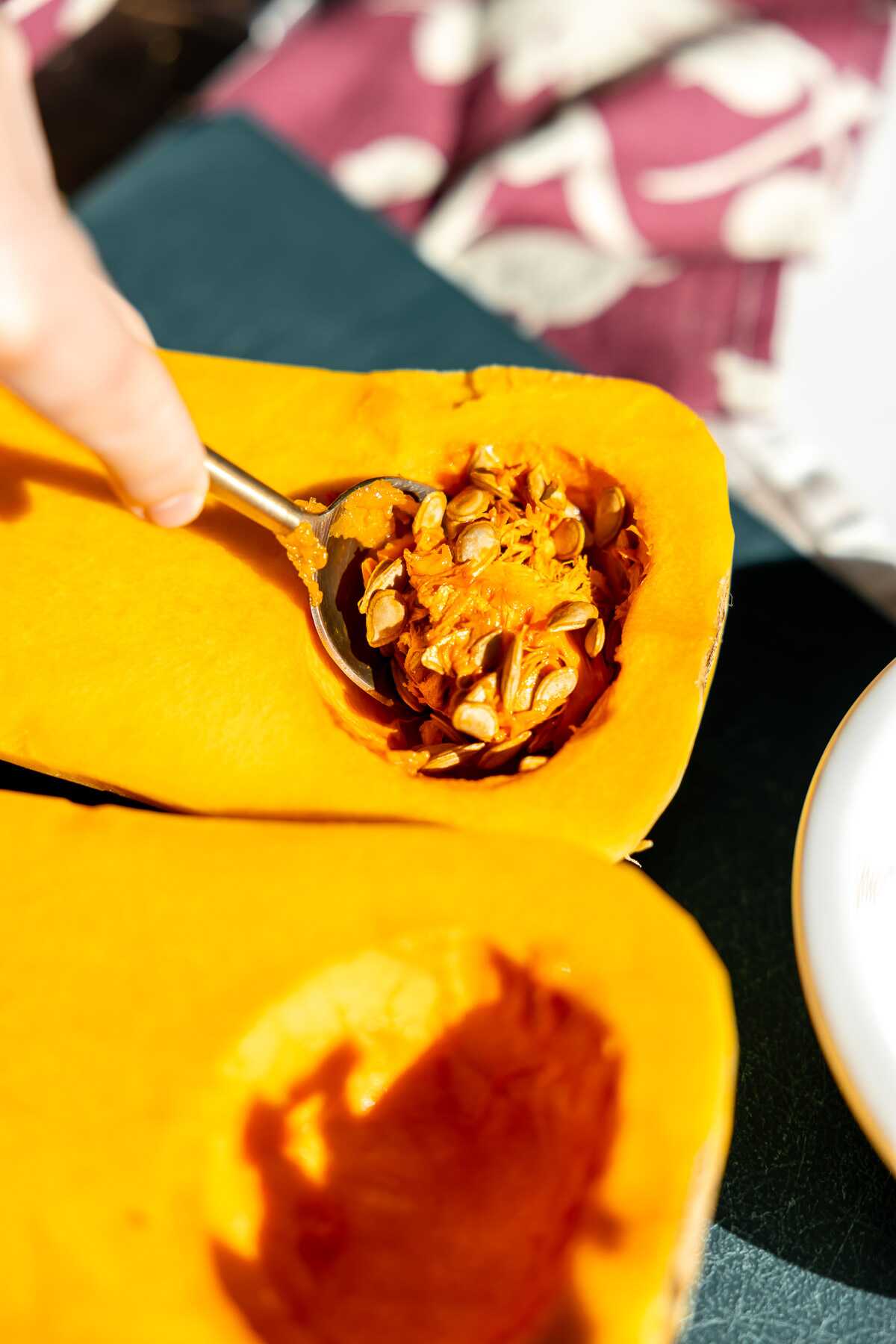 Scooping the seeds out of the bowl of the butternut squash. 