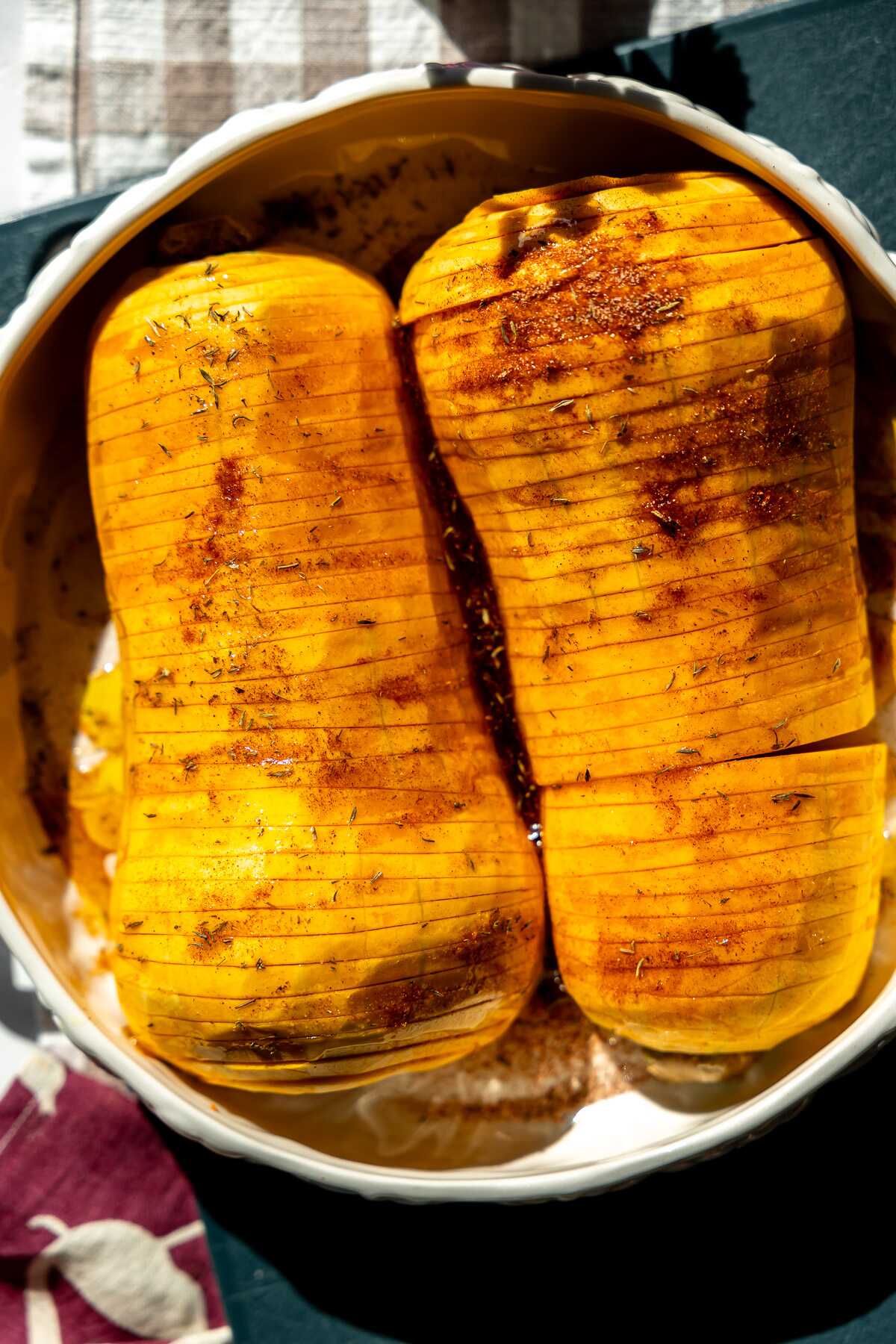 Hassleback butternut squash in a roasting pan ready for the oven. 