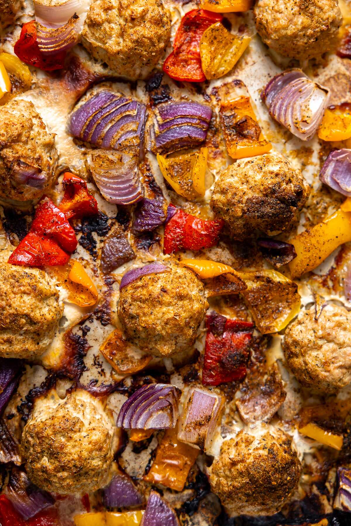 Baked cajun chicken meatballs and veggies on a sheet pan.