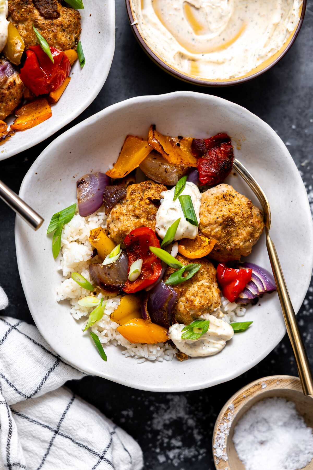 Sheet pan cajun chicken meatballs served over a bed of rice garnished with green onions.