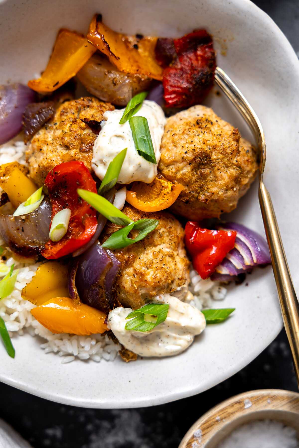 A close-up photo of cajun chicken meatballs in a bowl over rice. 